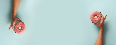 Tatlı çörek mavi arka plan üzerinde tutan el. Üstten Görünüm, düz yatıyordu. Kilo vermişsin, spor, fitness, diyet kavramı. Kopya alanı ile banner