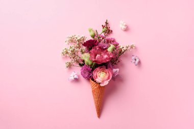 Yaz en az kavramı. Dondurma külahı pembe çiçekler ve yapraklar punchy pastel arka plan ile. Düz yatıyordu. Üstten Görünüm. Yaratıcı düzeni.