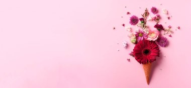 Yaz en az kavramı. Dondurma külahı pembe çiçekler ve yapraklar punchy pastel arka plan ile. Düz yatıyordu. Üstten Görünüm. Yaratıcı düzeni.