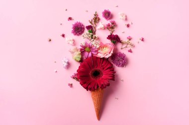 Yaz en az kavramı. Dondurma külahı pembe çiçekler ve yapraklar punchy pastel arka plan ile. Düz yatıyordu. Üstten Görünüm. Yaratıcı düzeni.