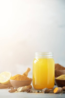 Baharatlı sağlıklı zerdeçal içki limon, zencefil, gri arka plan üzerinde siyah biber ile. Vegan sıcak içecek konsepti