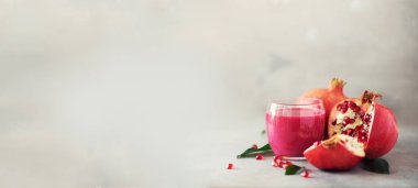 Bardak nar suyu gri beton zemin üzerine olgun nar meyve ile. Kopya alanı ile banner. Vegan, sağlıklı beslenme kavramı.