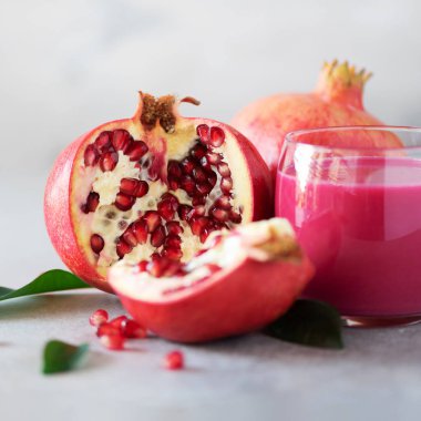 Bardak nar suyu gri beton zemin üzerine olgun nar meyve ile. Kopya alanı ile banner. Vegan, sağlıklı beslenme kavramı. Kare kırpma.