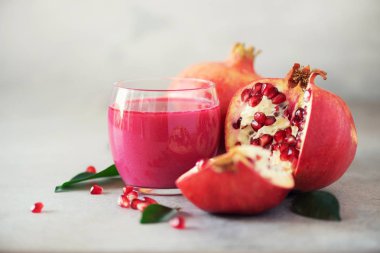 Bardak nar suyu gri beton zemin üzerine olgun nar meyve ile. Kopya alanı ile banner. Vegan, sağlıklı beslenme kavramı.