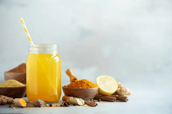 Zencefil, curcuma, kara biber limon suyuyla. Vegan sıcak içecek konsepti. Gri beton zemin üzerine portakal zerdeçal içki için malzemeler.