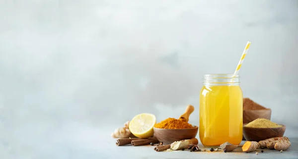 Gri beton zemin üzerine portakal zerdeçal içki için malzemeler. Zencefil, curcuma, kara biber limon suyuyla. Vegan sıcak içecek konsepti.