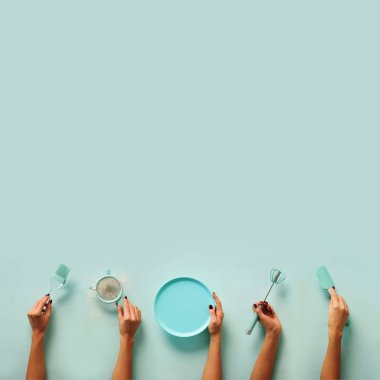 Holding mutfak araçları, elek, oklava, plaka, elek, fırça, çırpma teli, pişirme ve pastel mavi arka plan üzerinde pişirme spatula eller. Gıda çerçeve, fırında kavramı kopya alanı ile.