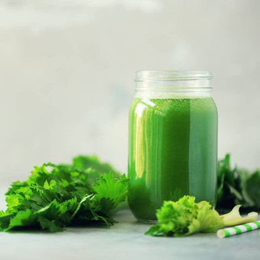 Bir şişe yeşil kereviz smoothie gri beton arka planda fotokopi alanı ile. Kare mahsul. Detoks için taze meyve suyu. Vegan, alkali sağlıklı beslenme konsepti