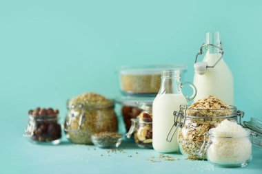 Vegan yerine süt süt. Cam şişe süt süt ve malzemeler üzerinde kopya alanı ile mavi arka plan ile. Temiz yemek, süt-free, vegan, Anti-Dostu, sağlıklı gıda kavramı