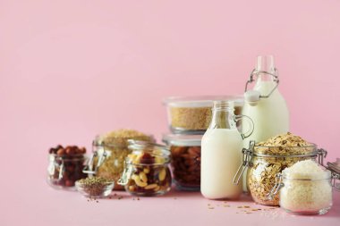 Vegan yerine süt süt. Non-süt süt ve malzemeler üzerinde kopya alanı ile pembe arka plan cam şişeler. Temiz yemek, süt-free, vegan, Anti-Dostu, sağlıklı gıda kavramı