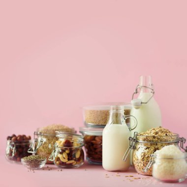 Vegan yerine süt süt. Non-süt süt ve malzemeler üzerinde kopya alanı ile pembe arka plan cam şişeler. Temiz yemek, süt-free, vegan, Anti-Dostu, sağlıklı gıda kavramı