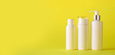 Sarı arka planda beyaz kozmetik tüpleri ve fotokopi alanı. Cilt bakımı, vücut bakımı, güzellik konsepti