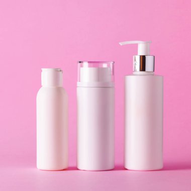 Pembe arka planda fotokopi alanı olan beyaz kozmetik tüpleri. Cilt bakımı, vücut bakımı, güzellik konsepti. Kare mahsul
