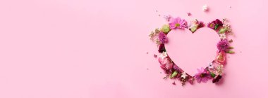 Pembe çiçekli yaratıcı bir düzen, yumruklu pastel arka planda kağıt kalp. Üst manzara, düz yatış. Bahar, yaz ya da bahçe konsepti. Kadın Günü hediyesi. Pankart