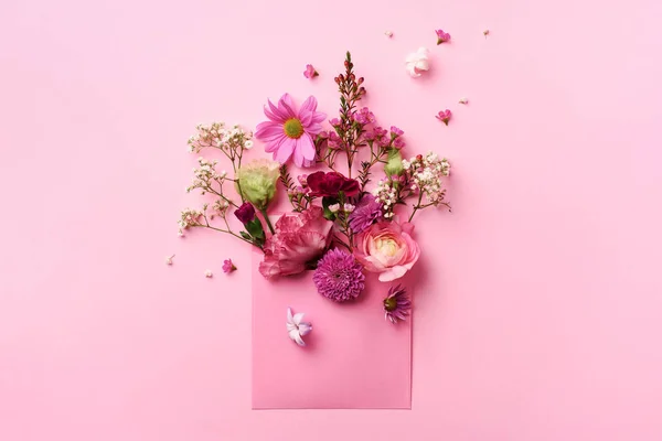 Sobre rosa con flores primaverales. Composición floral, diseño creativo. Asiento plano, vista superior. Concepto de primavera, verano o jardín. Regalo para el día de la mujer —  Fotos de Stock