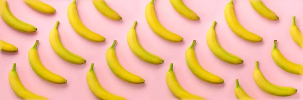 Geometriskt färgglatt fruktmönster. Bananer över rosa bakgrund. Banner. Högst upp. Popkonst design, kreativ sommar koncept. Minimal platt liggstil. — Stockfoto
