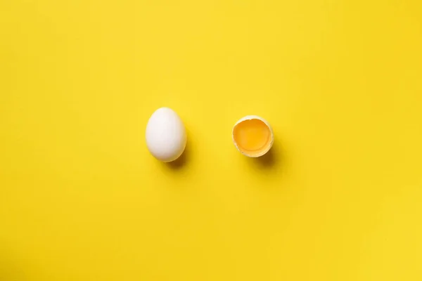 Food concept with broken egg and whole one on yellow background. Top view. Creative pattern in minimal style. Flat lay. — 스톡 사진