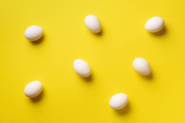 Sarı arka planda beyaz tavuk yumurtası olan yemek konsepti. Üst Manzara. Asgari tarzda yaratıcı bir model. Düz yatıyordu.