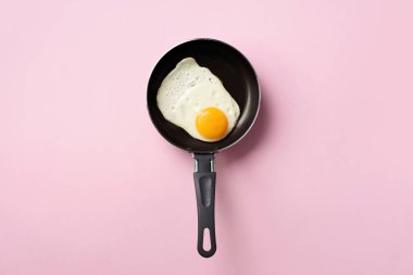 Pembe arka planda tavada pişmiş yumurta ile yaratıcı gıda konsepti. Üst Manzara. Asgari tarzda yaratıcı bir model. Düz yatıyordu.