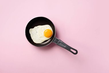 Pembe arka planda tavada pişmiş yumurta ile yaratıcı gıda konsepti. Üst Manzara. Asgari tarzda yaratıcı bir model. Düz yatıyordu.