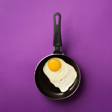 Menekşe kaplama tavada yumurta pişirilmiş yaratıcı gıda konsepti. Üst Manzara. Asgari tarzda yaratıcı bir model. Düz yatıyordu. Kare mahsul