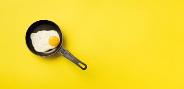 Tavada pişmiş yumurta ve sarı arka plan üzerine yaratıcı gıda konsepti. Üst Manzara. Asgari tarzda yaratıcı bir model. Düz yatıyordu.