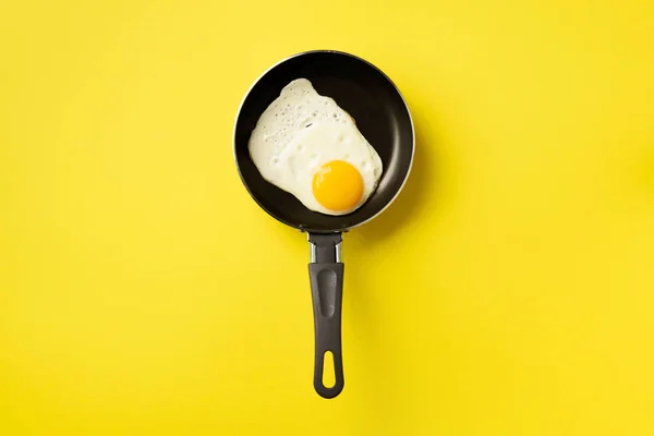 Δημιουργική ιδέα φαγητού με τηγανητό αυγό σε τηγάνι σε κίτρινο φόντο. Στο πάνω μέρος. Δημιουργικό μοτίβο σε minimal στυλ. Επίπεδη. — Φωτογραφία Αρχείου