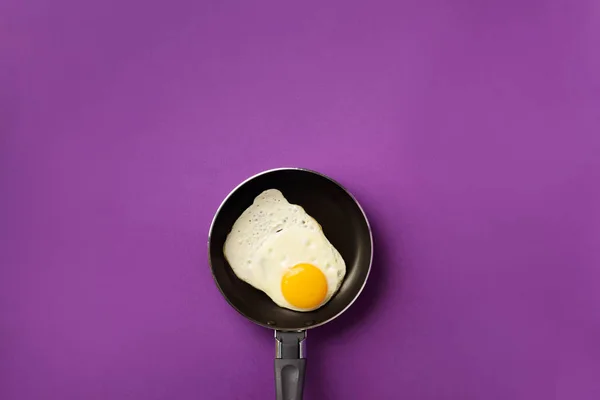 Δημιουργική ιδέα τροφίμων με τηγανητό αυγό σε τηγάνι σε βιολετί φόντο. Στο πάνω μέρος. Δημιουργικό μοτίβο σε minimal στυλ. Επίπεδη — Φωτογραφία Αρχείου