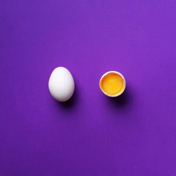Food concept με σπασμένο αυγό και ολόκληρο σε βιολετί φόντο. Στο πάνω μέρος. Δημιουργικό μοτίβο σε minimal στυλ. Επίπεδη. Τετραγωνική καλλιέργεια — Φωτογραφία Αρχείου