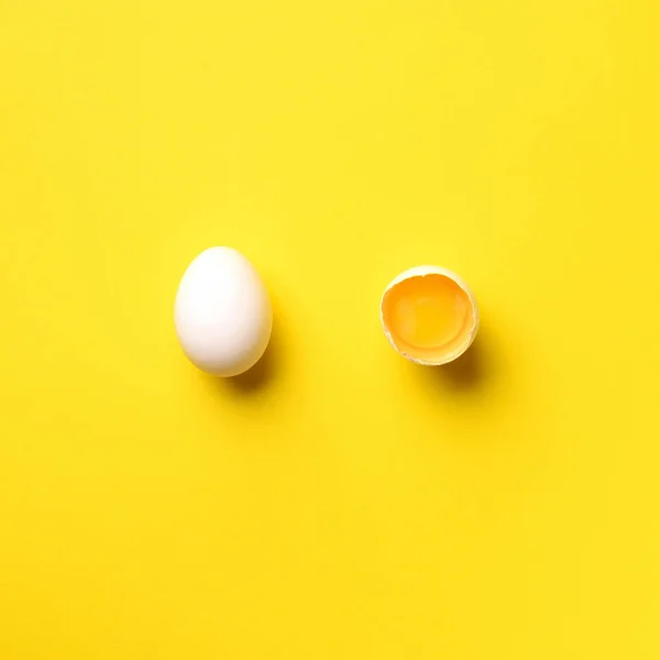 Food concept με σπασμένο αυγό και ολόκληρο σε κίτρινο φόντο. Στο πάνω μέρος. Δημιουργικό μοτίβο σε minimal στυλ. Επίπεδη. Τετραγωνική καλλιέργεια — Φωτογραφία Αρχείου