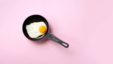 Pembe arka planda tavada pişmiş yumurta ile yaratıcı gıda konsepti. Üst Manzara. Asgari tarzda yaratıcı bir model. Düz yatıyordu.