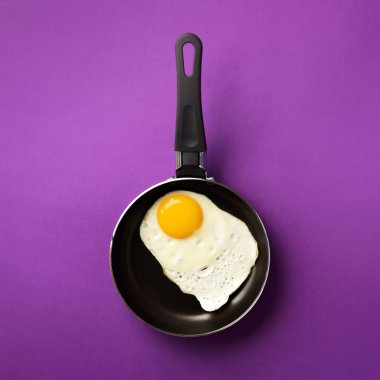 Menekşe kaplama tavada yumurta pişirilmiş yaratıcı gıda konsepti. Üst Manzara. Asgari tarzda yaratıcı bir model. Düz yatıyordu. Kare mahsul