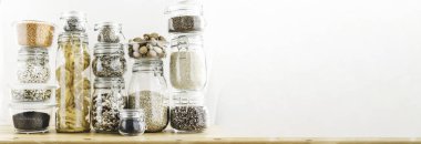 Tahta masadaki cam kaplarda tahıl ürünleri ve makarna içeren pankart. Sağlıklı yemek, temiz yemek, sıfır atık konsepti. Dengeli diyet yemekleri. Boşluğu kopyala