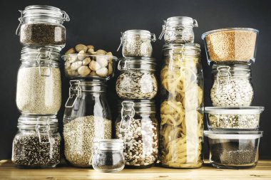 Tahta masadaki cam kaplarda tahıl ürünleri ve makarna çeşitleri. Sağlıklı yemek, temiz yemek, sıfır atık konsepti. Dengeli diyet yemekleri