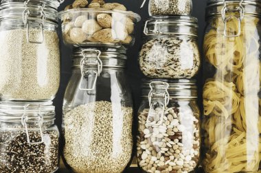 Tahta masadaki cam kaplarda tahıl ürünleri ve makarna çeşitleri. Sağlıklı yemek, temiz yemek, sıfır atık konsepti. Dengeli diyet yemekleri