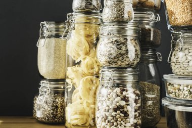 Tahta masadaki cam kavanozlarda pişmemiş tahıl, tahıl ve makarna çeşitleri. Sağlıklı yemek, temiz yemek, sıfır atık konsepti. Dengeli diyet yemekleri