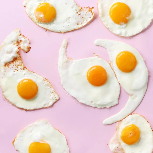 Fried eggs or scrambled eggs pattern on pink background. Creative food concept. Top view. Square crop