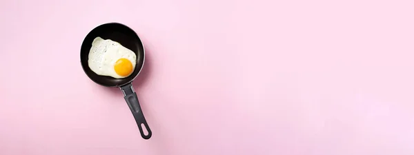 Conceito de comida criativa com ovo frito na panela sobre fundo rosa. Vista superior. Padrão criativo em estilo mínimo. Deitado. Banner — Fotografia de Stock