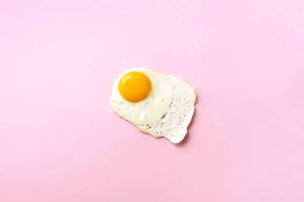 Um ovo frito no fundo de papel rosa. Conceito de comida criativa em estilo mínimo. Vista superior — Fotografia de Stock