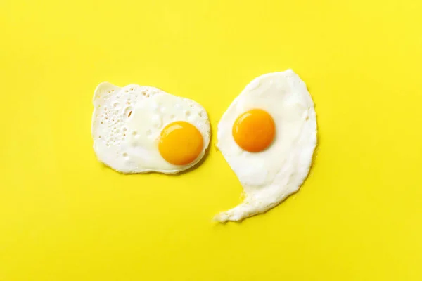 Dois ovos fritos no fundo de papel amarelo. Conceito de comida criativa em estilo mínimo. Vista superior — Fotografia de Stock