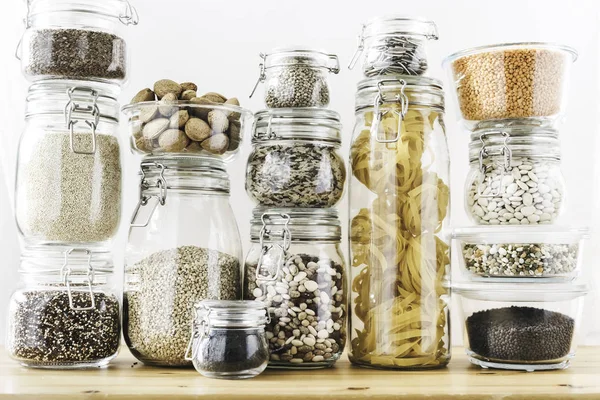 Assortment of grain products and pasta in glass storage containers on wooden table. Healthy cooking, clean eating, zero waste concept. Balanced dieting food