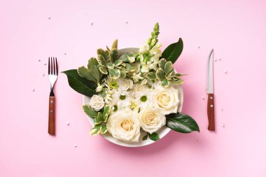 Tabakta beyaz çiçekler, çatal, pastel pembe arka planda bıçak. Sağlıklı beslenme, vejetaryen diyeti. Yaratıcı düzen. Üst manzara, düz uzanma