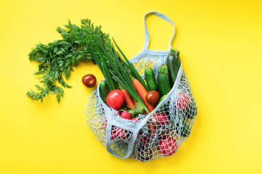 Sarı kağıtta organik yeşil sebzeli çevre dostu ağ torbası. Düz yerde, üst tarafta. Sıfır atık, plastiksiz konsept. Sağlıklı beslenme ve detoks.