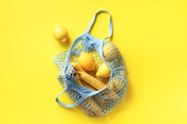 İçinde organik muz, portakal ve sarı kağıttan yapılmış limonlar olan alışveriş torbası. Düz yerde, üst tarafta. Sıfır atık, plastiksiz konsept. Sağlıklı beslenme ve detoks. Yaz meyveleri