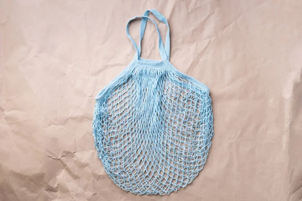 Reusable net bag or mesh shopper on craft paper background. Zero waste, plastic free concept. Top view. Eco friendly mesh shopper. Banner with copy space