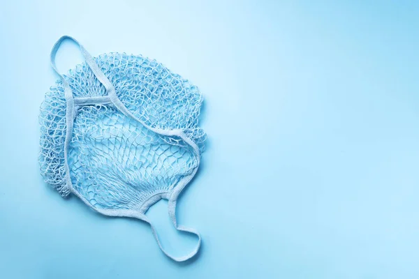 Borsa a rete riutilizzabile o shopper in rete su sfondo di carta blu. Zero sprechi, concetto di plastica libera. Vista dall'alto. Eco shopper maglia amichevole. Banner con spazio di copia — Foto Stock