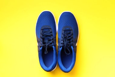 Sarı arka planda bir çift mavi spor ayakkabı. Üst görünüm, boşluğu kopyala. Spor, spor ve spor konsepti. Sağlıklı yaşam tarzı