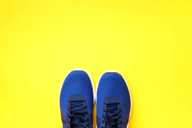 Sarı arka planda bir çift mavi spor ayakkabı. Üst görünüm, boşluğu kopyala. Spor, spor ve spor konsepti. Sağlıklı yaşam tarzı