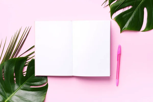 Monstera verde, folhas de palma, coco, cadernos sobre fundo rosa. Espaço de trabalho do escritor do blog feminino, de volta ao conceito de escola. Deitado. Vista superior . — Fotografia de Stock