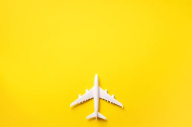 Seyahat, tatil konsepti. Sarı arka planda, kopyalama alanı olan beyaz model bir uçak. Üst Manzara. Düz yatıyordu. Asgari biçim tasarımı.